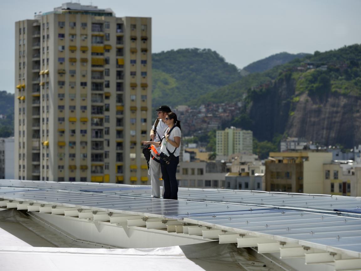 Two people beside the photovoltaic panels on the roof of Brazil’s Maracanã football stadium. 