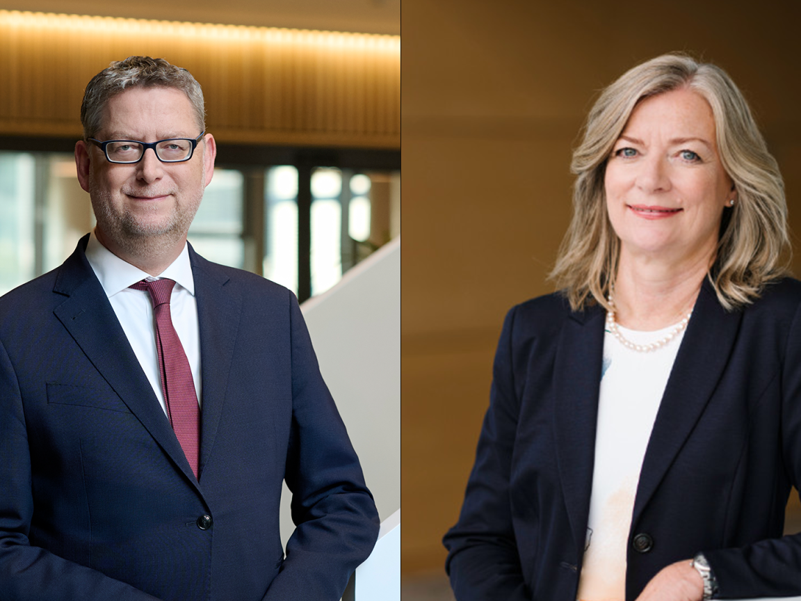 Ein Mann und eine Frau in Businesskleidung blicken in die Kamera.