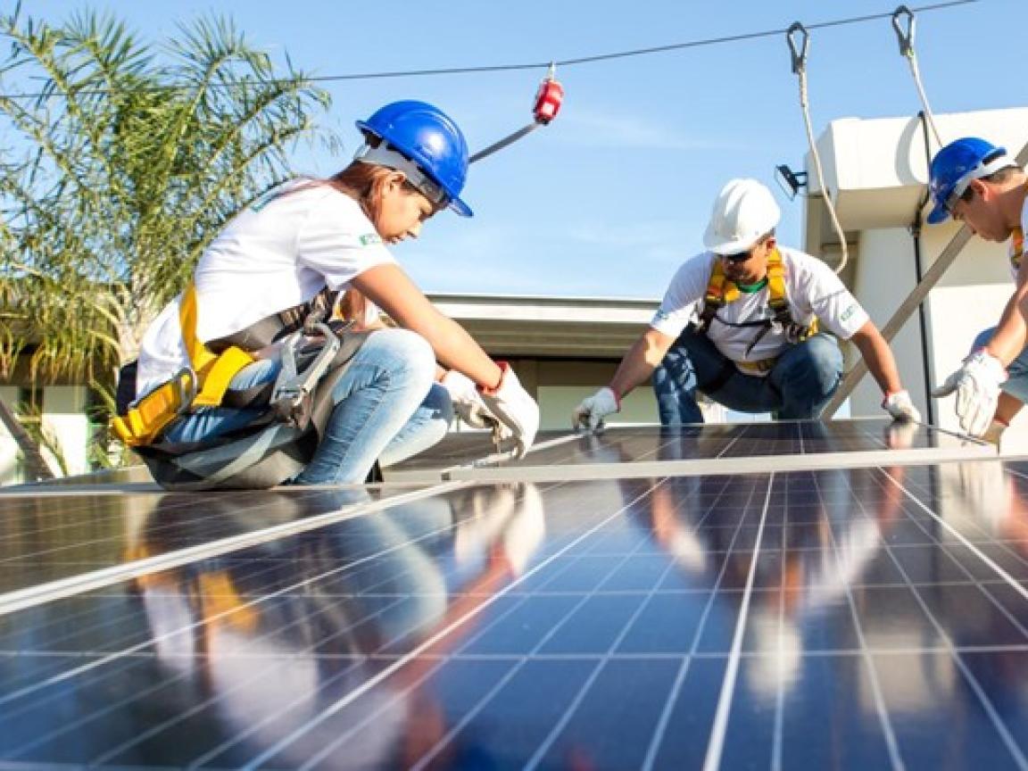 Technicians installing solar panels on a rooftop in Brazil. 