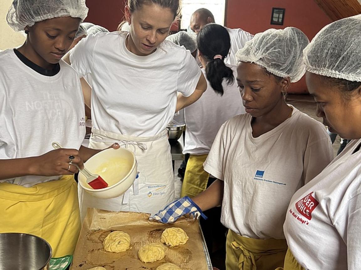 Bäckermeisterin Sarah Braun steht an einem Tisch mit drei angehenden Bäckerinnen aus Madagaskar.
