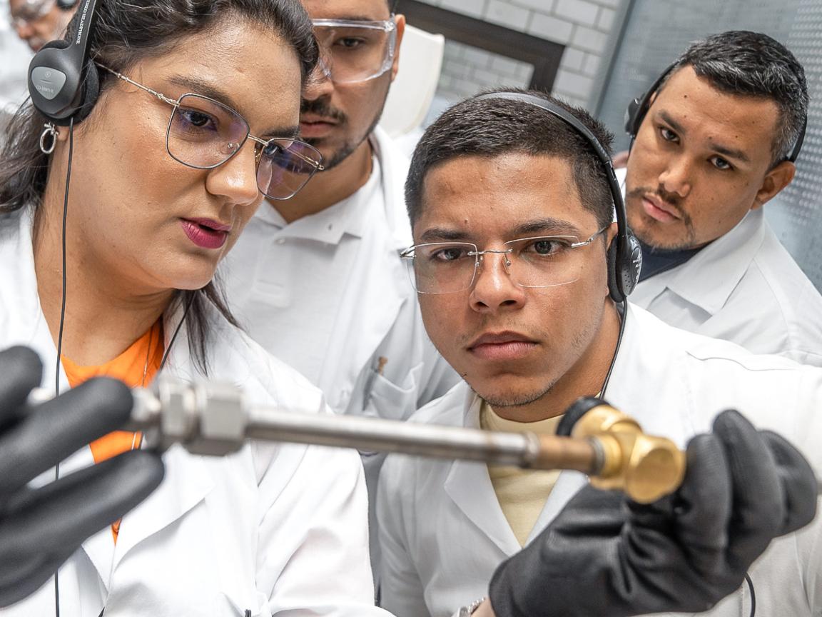 Four people look at a technical device during a training session.