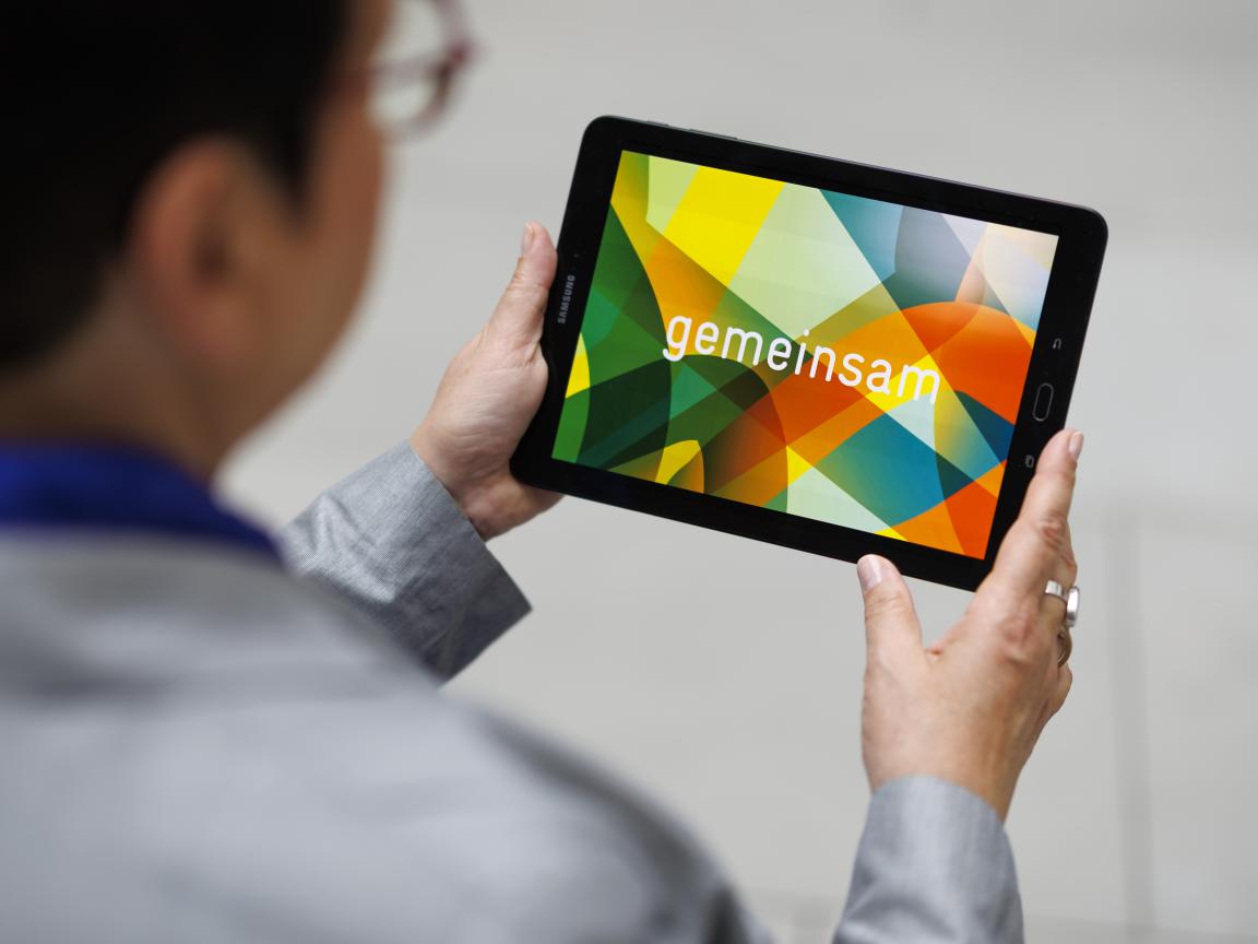 Eine Frau schaut auf ein Tablet, das sie in den Händen hält.