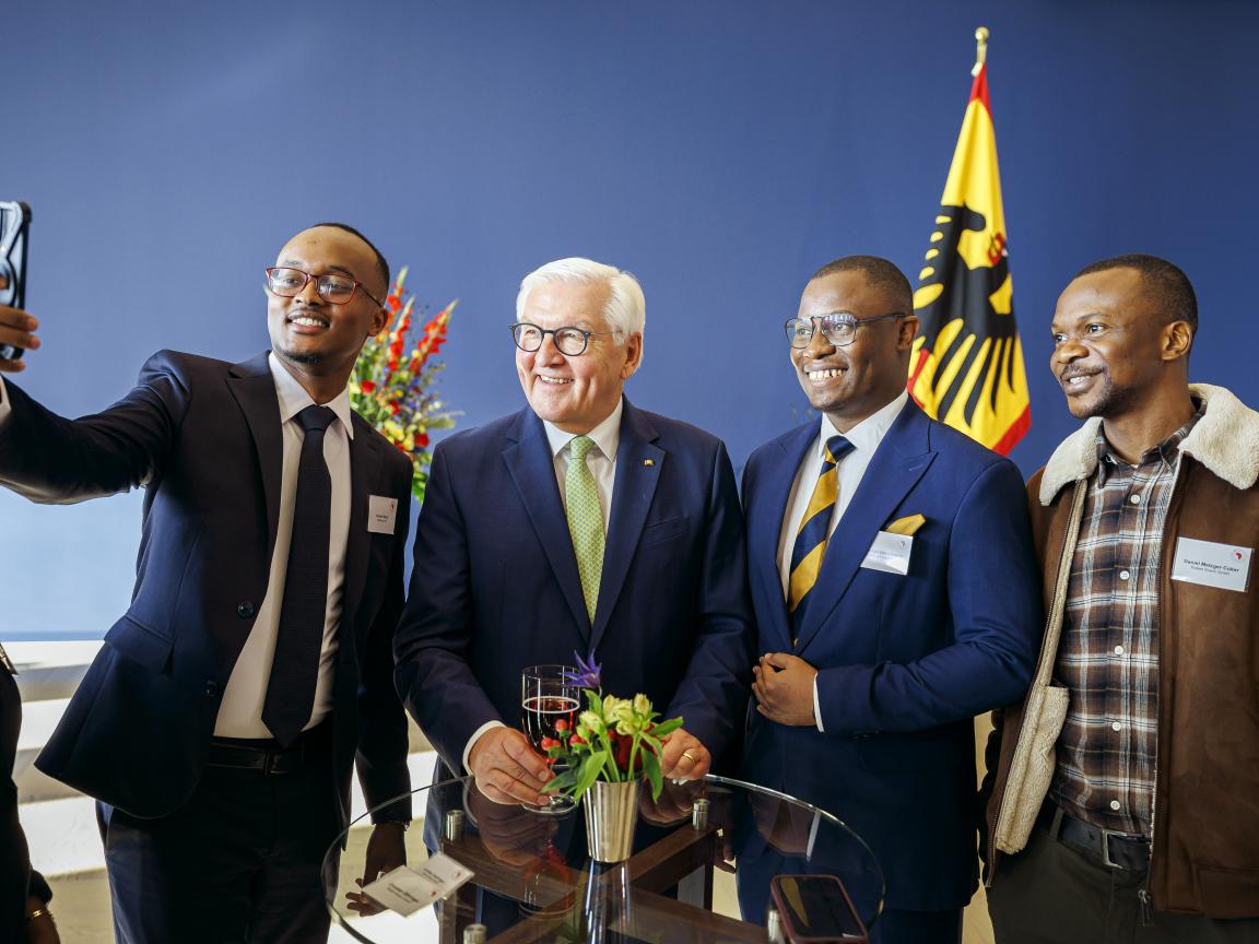 Drei der Stipendiaten machen ein Selfie mit Bundespräsident Frank-Walter Steinmeier im Schloss Bellevue. Alle grinsen ins Smartphone.