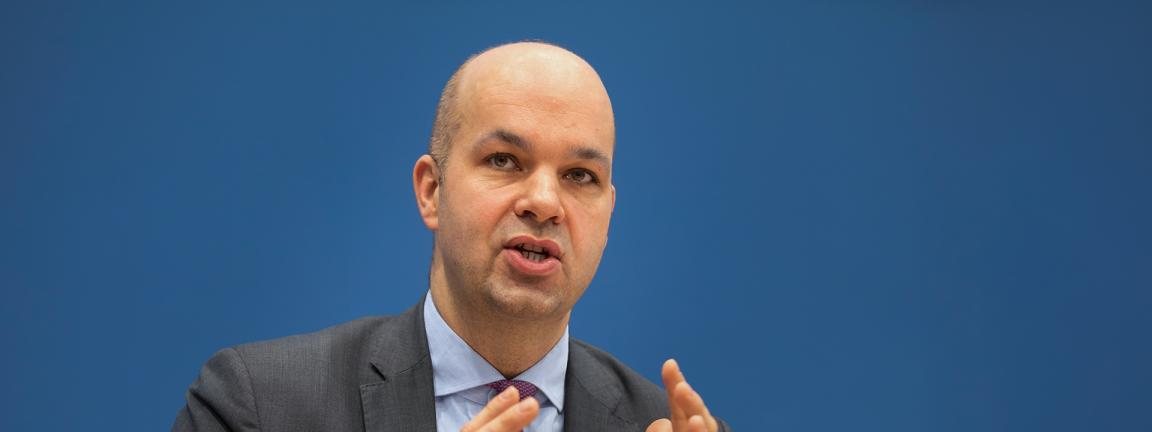 Marcel Fratzscher, im Anzug mit Krawatte vor blauem Hintergrund, der beim Sprechen beide Hände gestikulierend vor sich hält.