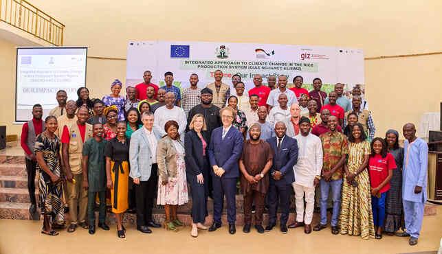 eine große Anzahl von Menschen posieren vor einem Veranstaltungsbanner.