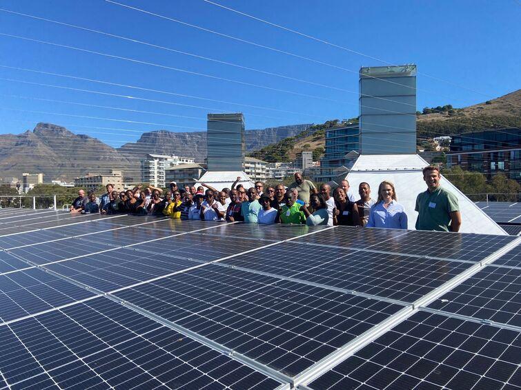 A group of people standing next to many solar panels