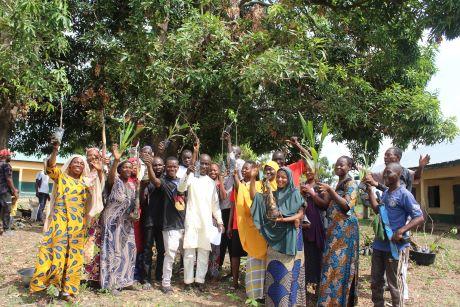 Zu sehen ist ein Gruppenfoto. Die Personen, die posieren halten Pflanzen in die Höhe.