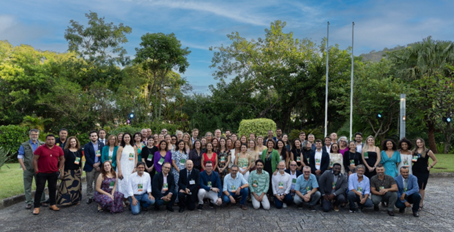 Großes Gruppenfoto der Vertreter von Partnerinstitutionen und GIZ Brasilien vor grüner Kulisse im deutschen Konsulat.