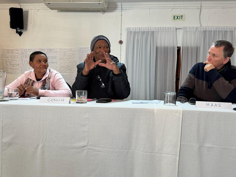 3 people sitting at a table and one of them is explaining something