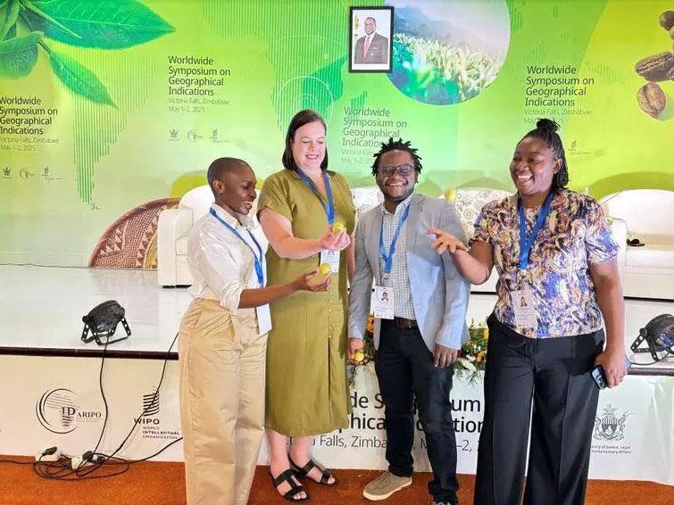 Bei einem Event zu "worldwide Symposium on Geopgraphical Indications" lächeln vier Personen für die Kamera und halten etwas kleines, rundes und gelbes in der Hand