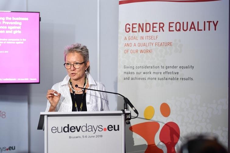 Frau steht an einem Pult und redet in ein Mikrofon