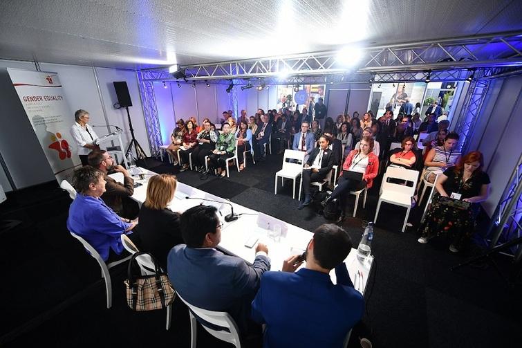 Personen sitzen an einem Tisch und schauen in das ihnen gegenüber sitzende Publikum