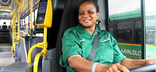 Frau in einem grünen Oberteil sitzt auf dem Fahrersitz in einem Bus