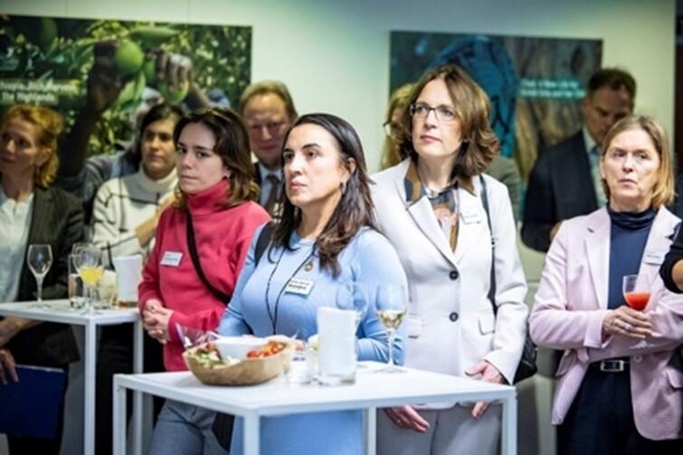 Ein paar Frauen stehen um weiße Tische und schauen nach vorne