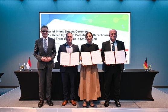 Vertreter von Neuman & Esser (NEA) Ltd., Hydrogen de France (HDF) Energy, and GIZ halten die unterzeichneten Absichtserklärungen in die Kamera.