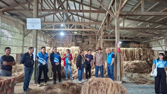 Vertreter:innen des Farmers Alternative for Self-Reliance Multi-Purpose Cooperative (FARSMCO) und GIZ in einer Scheune zwischen Strohballen.