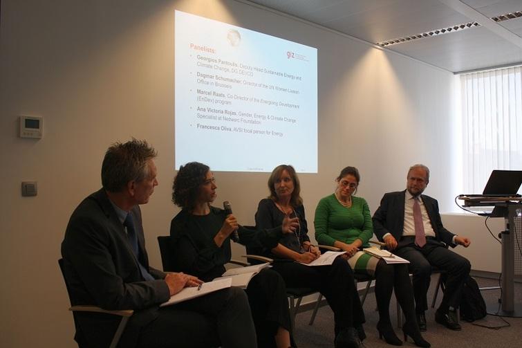 Vier Personen hören einer Person zu, die ein Mikrofon in der Hand hat.