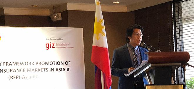 Ein Vertreter der Philippinischen Regierung spricht an einem Rednerpult, hinter ihm die philippinische Flagge.