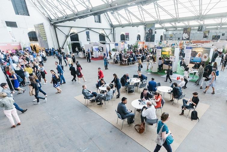 Menschen sitzen oder stehen verteilt in einer Halle