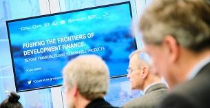 Bildschirm mit der Aufschrift "Pushing the frontiers of development Finance"