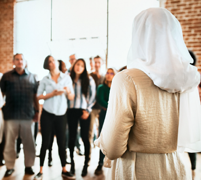 A woman standing in front of gathered people.