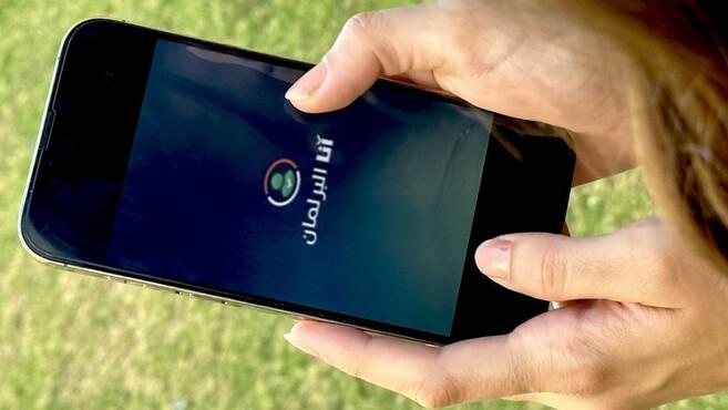 Hand holding a smartphone showing the Logo of the application "I am Parliament"