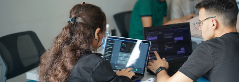 Two persons sitting at a desk working on their Laptops
