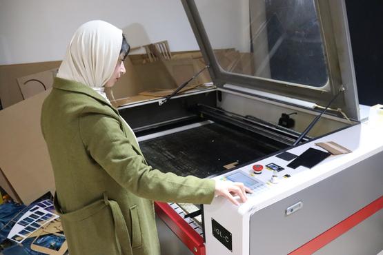 A woman operating a laser cutter