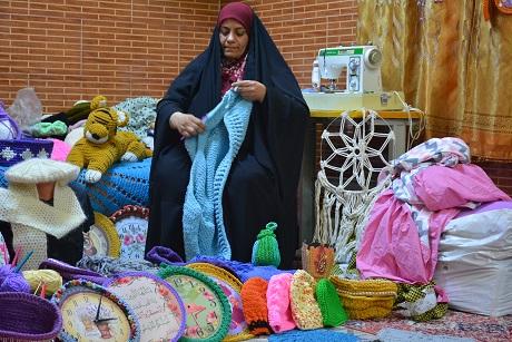 A woman knitting surrounded by her products
