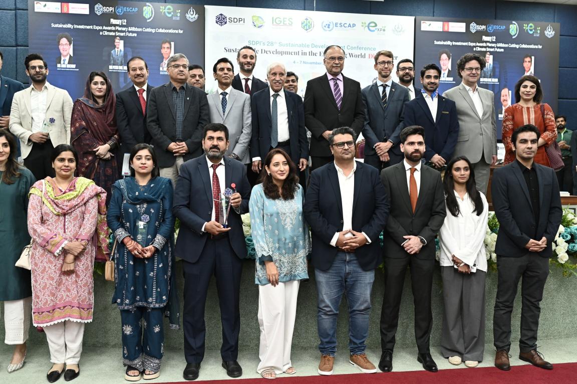 Two rows of participants, including men and women, pose for a photo at the conference.