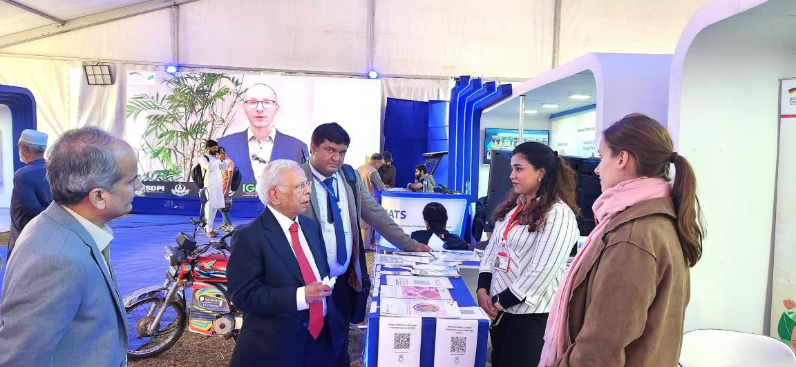 Conference attendees and former Governor State Bank Pakistan interact with female staff at the PGCEP stall.
