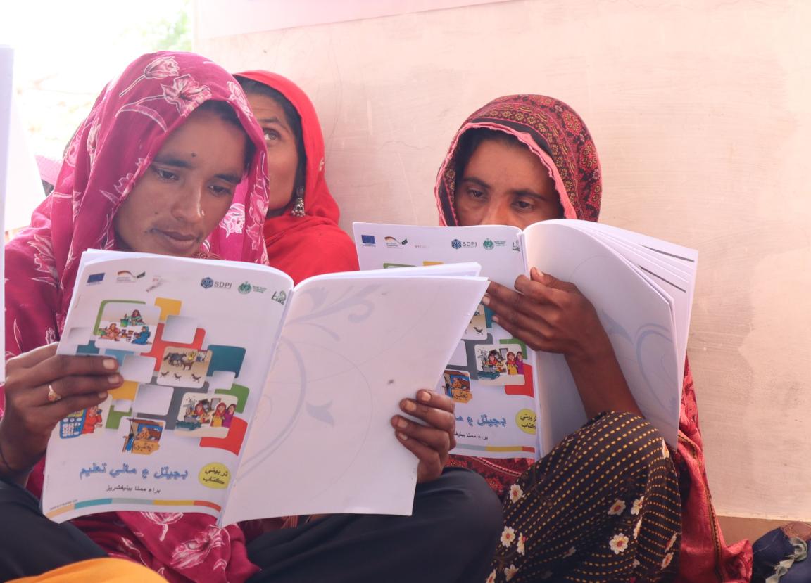 Two women from Sindh reading a manual on digital literacy