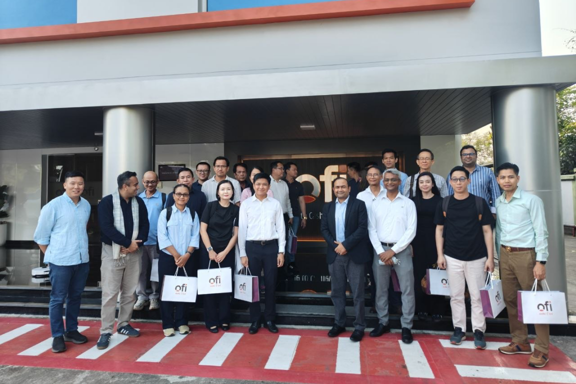 A group of people in front a building of Olam Food Ingredients (ofi), some are holding paper bags of ofi.