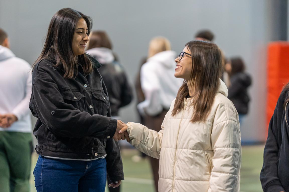 Two young participants smiling and shaking hands during a Superschools exchange activity.
