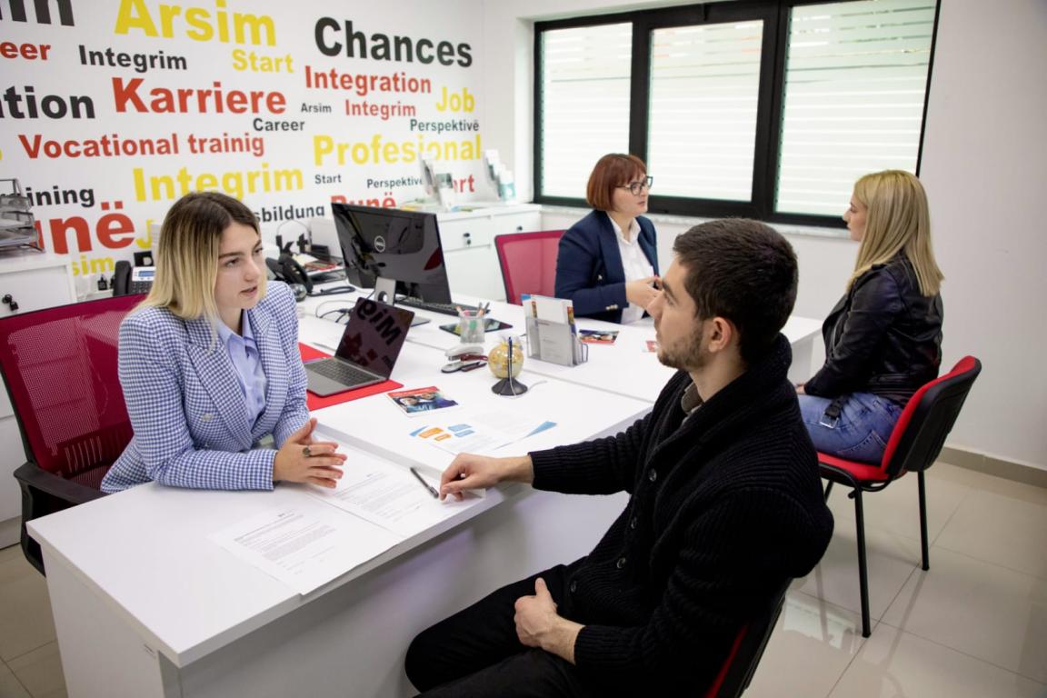 Four people having one-on-one consultations at desks in a vocational guidance and employment support office.