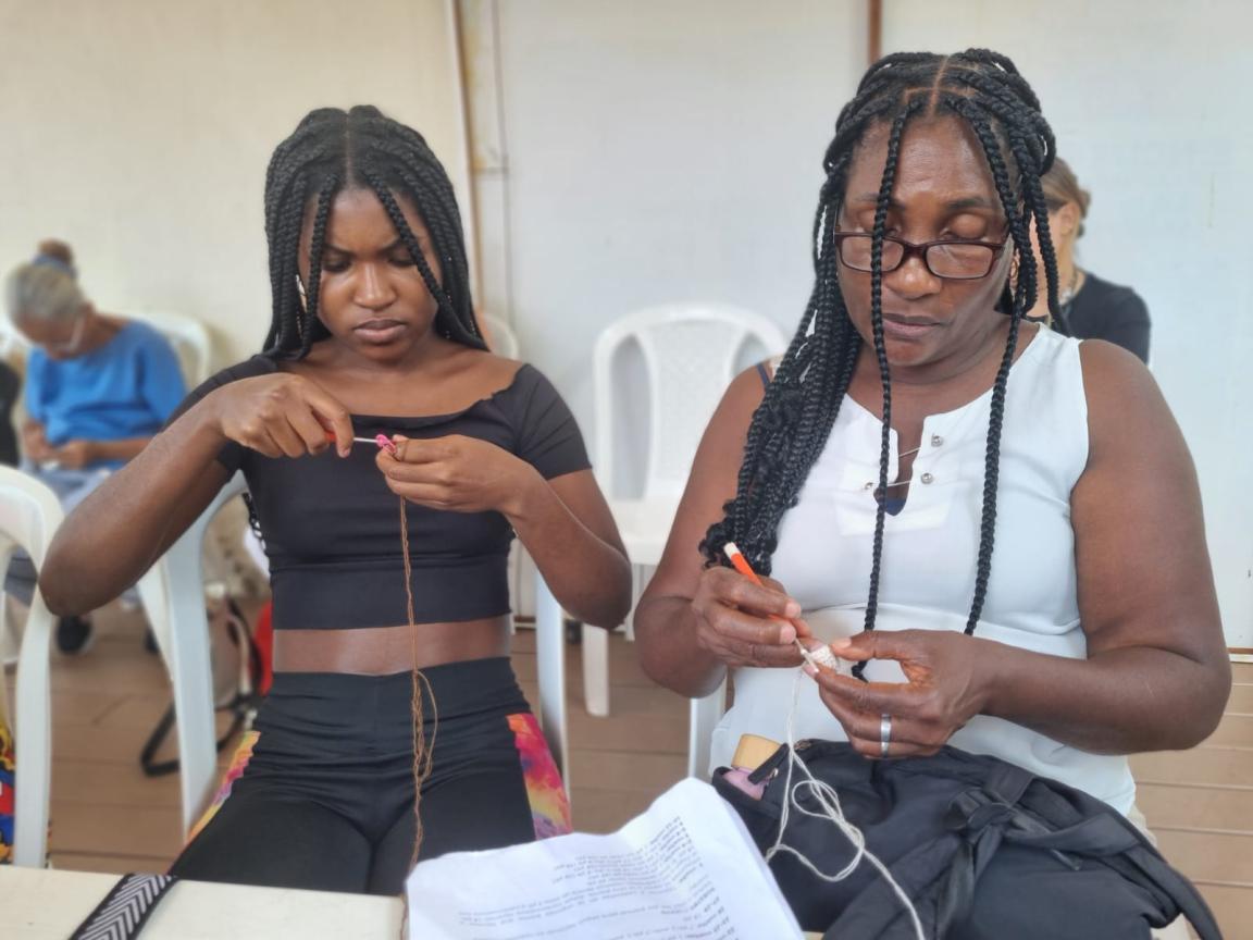 Dos mujeres negras sentadas tejiendo.