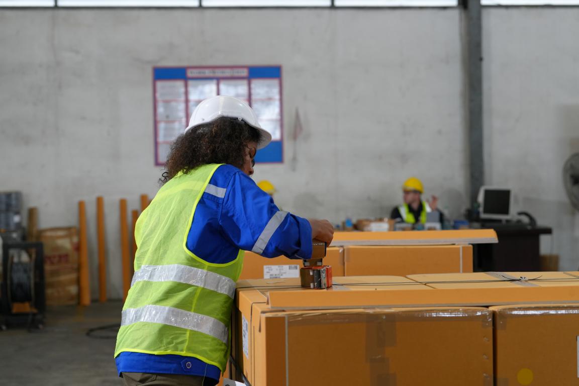 A woman wearing a high-visibility vest stands at a border control counter