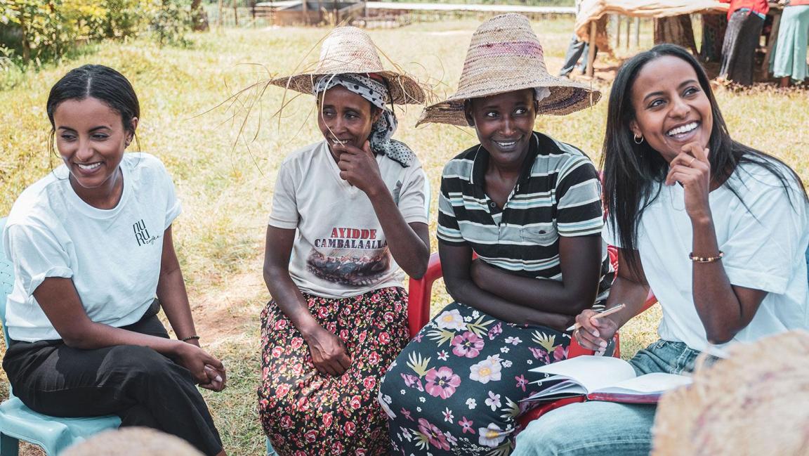 Vier Frauen sitzen, reden und lächeln