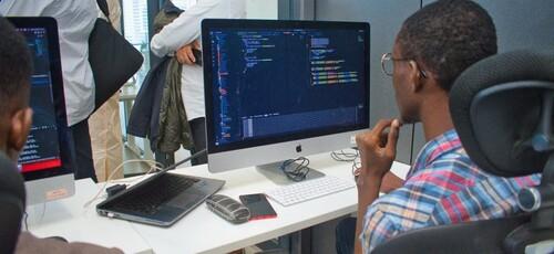A young man programming on a computer in a classroom.