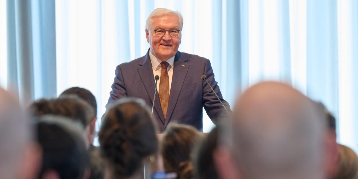 Federal President Frank-Walter Steinmeier giving a speech in front of the GIZ employees, who are seen from behind.