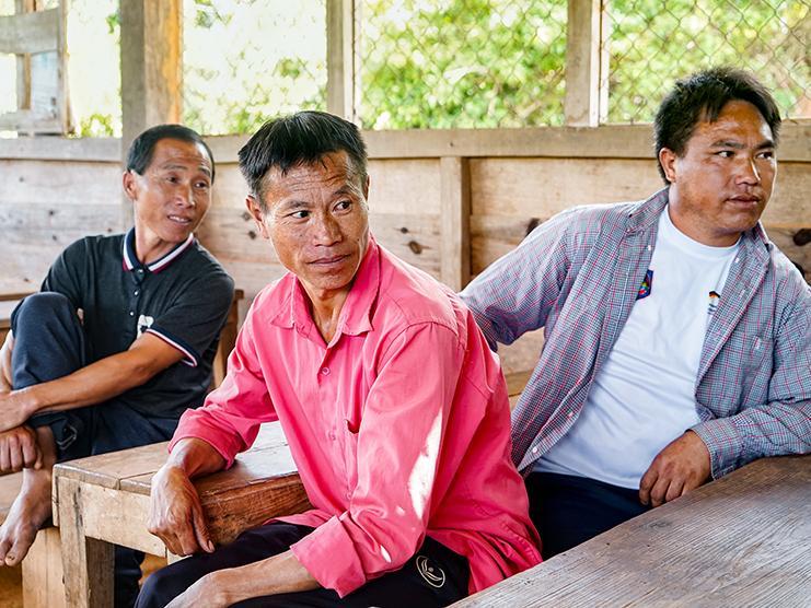 drei Männer sitzen an Tischen