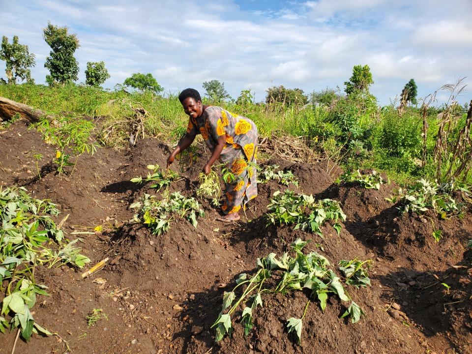 A woman stands in a field of crops and smiles.