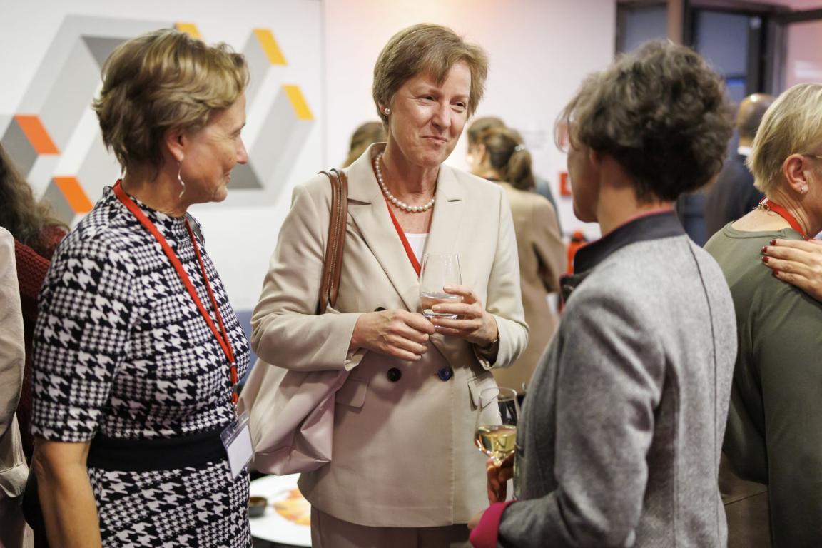 Drei Frauen stehen beieinander, eine redet, zwei hören zu