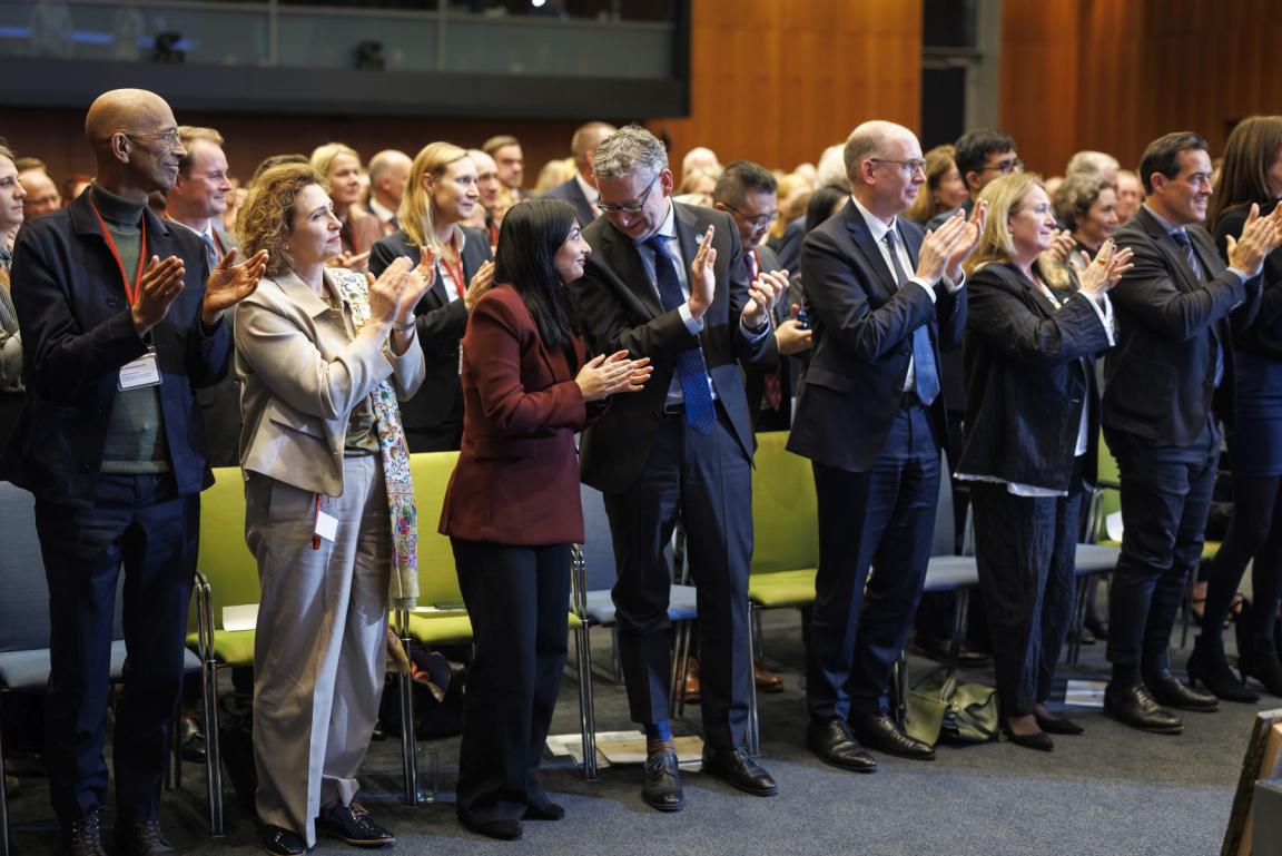 Mehrere Menschen stehen nebeneinander und klatschen bzw. reden miteinander