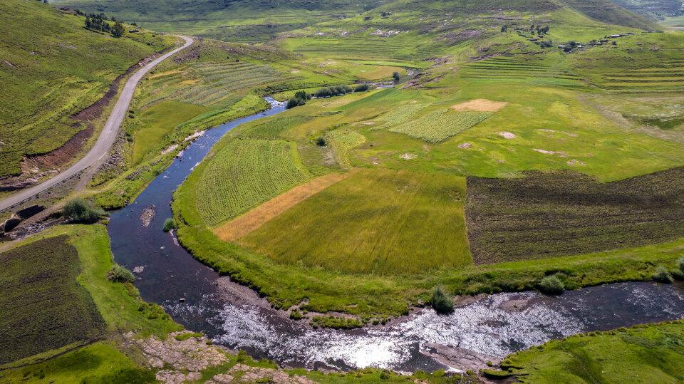 Eine weite grüne Landschaft in Lesoto, durch die sich ein großer Fluss schlängelt. 