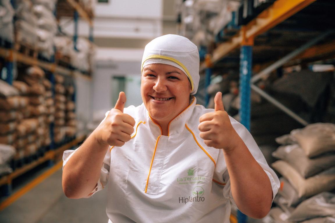 Eine Peson mit weißer Schutzkleidung streckt beide Daumen in die Luft und lächelt