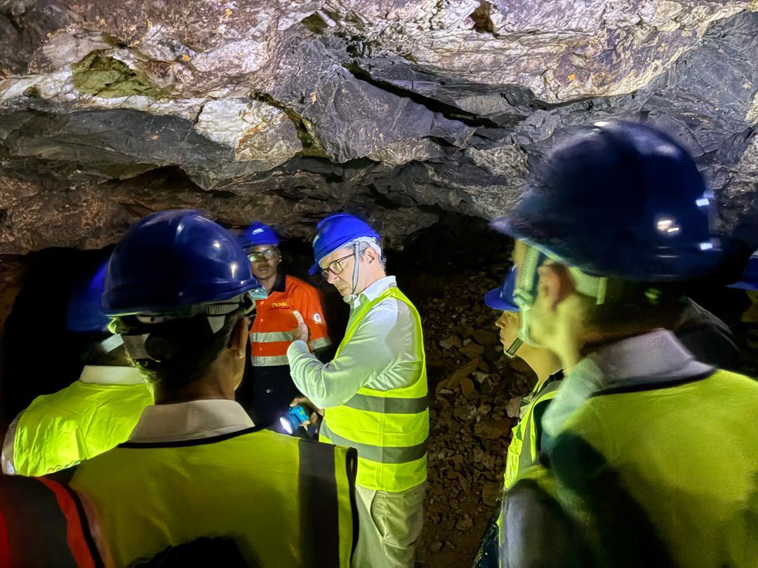 Mehrere Männer mit gelben Warnwesten stehen in einem Tunnel und leuchten mit einer Taschenlampe an die Decke des Tunnels. 