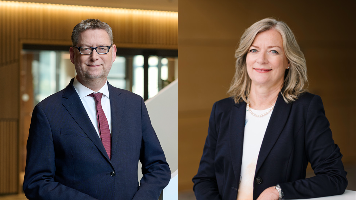 Ein Mann und eine Frau in Businesskleidung blicken in die Kamera.