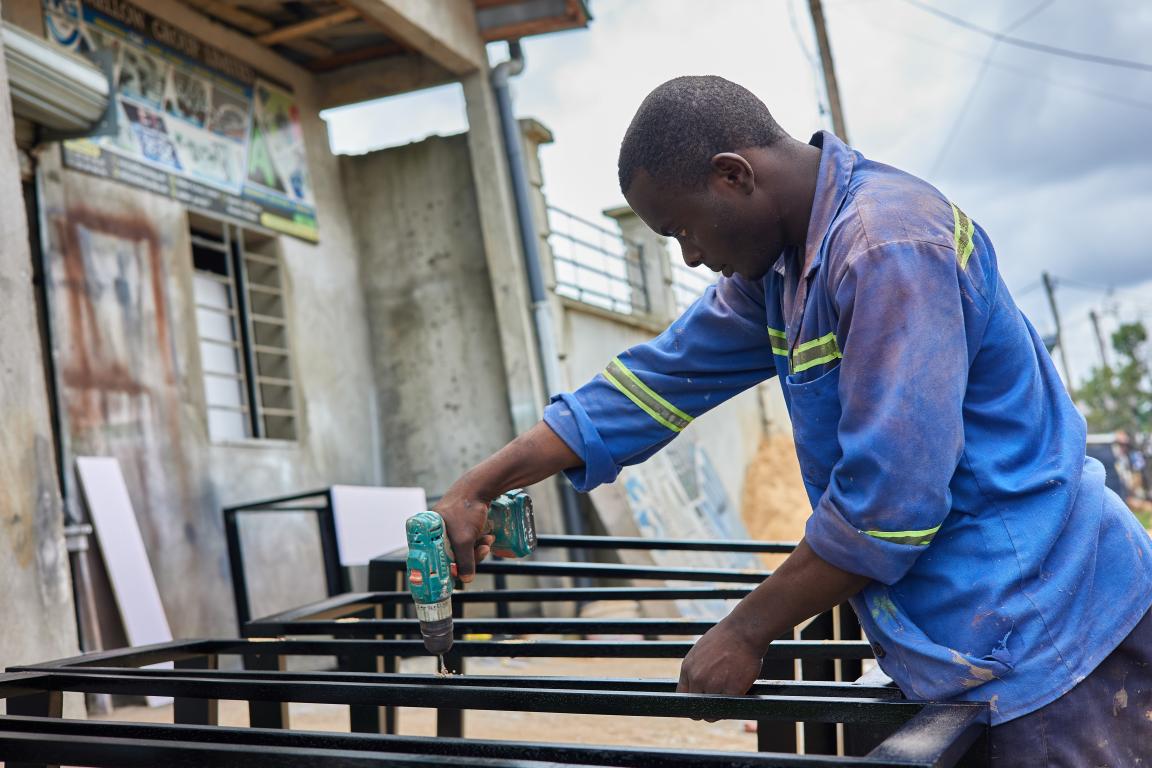 Ein Mann arbeitet mit einem Werkzeug an einem Ständer aus Stahl
