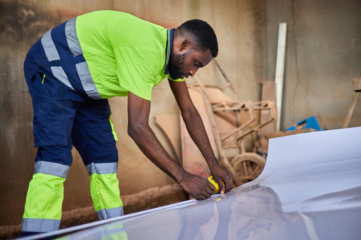 Ein Mann setzt mit einem Stift eine Markierung auf ein Blech am Boden